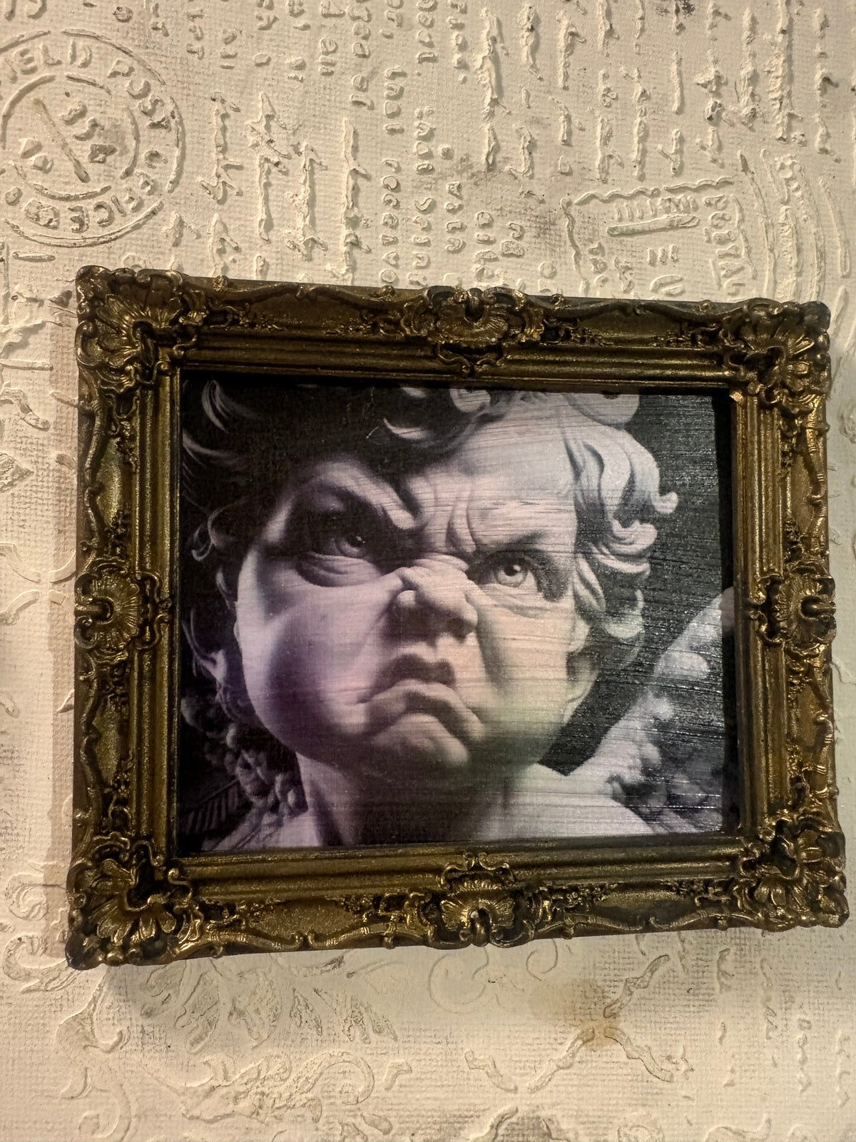 Cadre en plâtre de résine Shabby Chic PL035 — Ange Courrouцé, angelot au regard sombre et froncé, portrait noir et blanc aux teintes violacées dans un cadre baroque doré vieilli